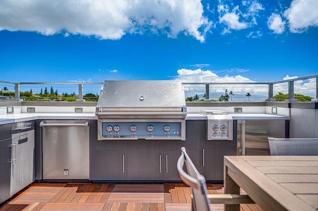 view of patio with grilling area, a wooden deck, and an outdoor kitchen