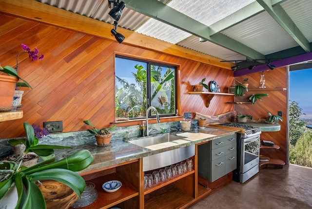 kitchen with stainless steel range with gas cooktop, wood walls, sink, and beamed ceiling