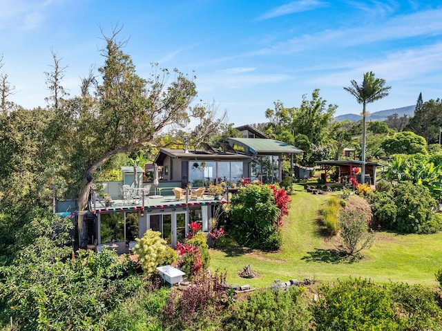 back of house with a lawn and a mountain view