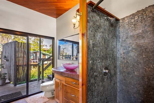 bathroom with a tile shower, vanity, wood ceiling, and toilet