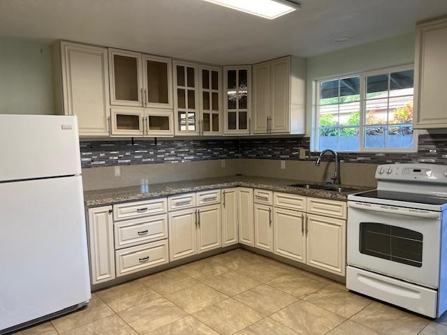 kitchen with sink, white appliances, light tile floors, and tasteful backsplash