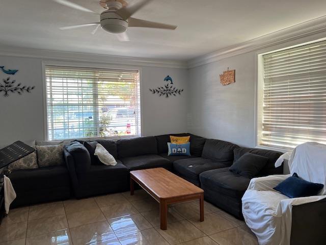 living room with ceiling fan, ornamental molding, and light tile patterned flooring