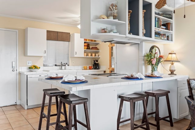 kitchen featuring white cabinets, tile counters, a kitchen bar, and dishwasher