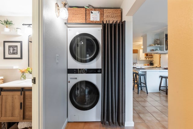 clothes washing area featuring light tile patterned floors and stacked washing maching and dryer