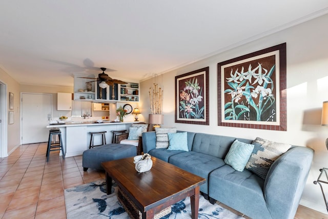 living room featuring ceiling fan, light tile patterned floors, and crown molding