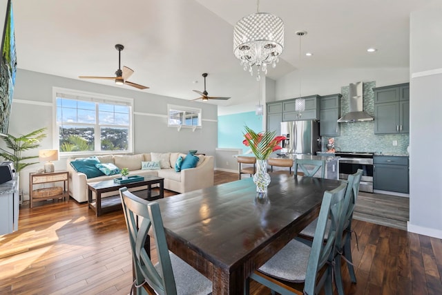 dining space featuring dark wood-style floors, ceiling fan with notable chandelier, lofted ceiling, and baseboards