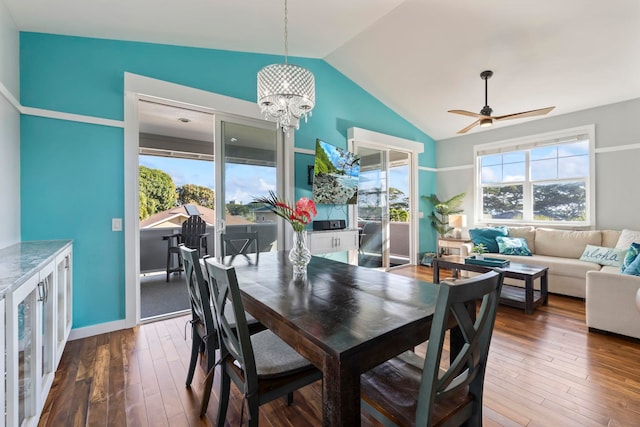 dining space with lofted ceiling, ceiling fan with notable chandelier, wood finished floors, and a wealth of natural light