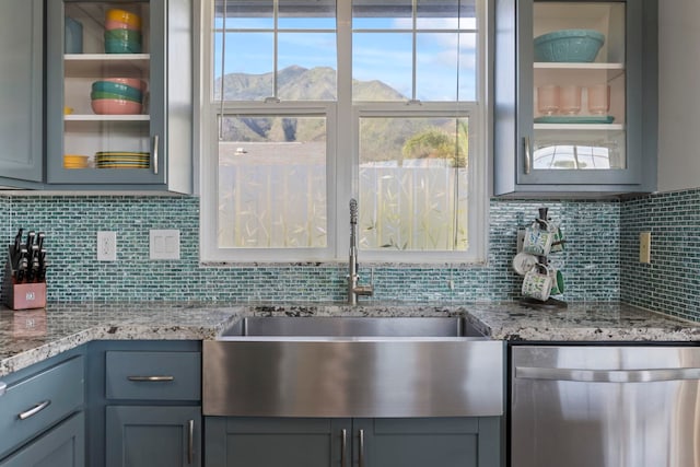 kitchen featuring backsplash, glass insert cabinets, a sink, a mountain view, and dishwasher