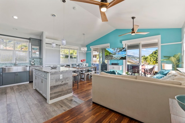 kitchen with light stone counters, pendant lighting, a sink, and gray cabinetry