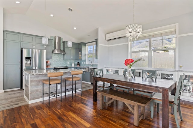 dining room featuring dark wood-style floors, vaulted ceiling, an AC wall unit, and an inviting chandelier