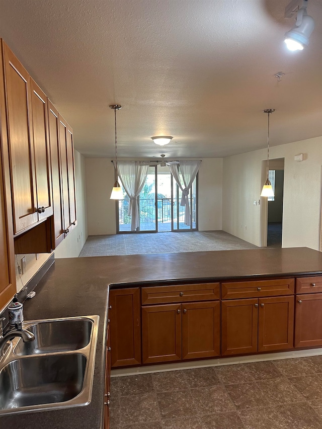 kitchen with kitchen peninsula, pendant lighting, a textured ceiling, and sink