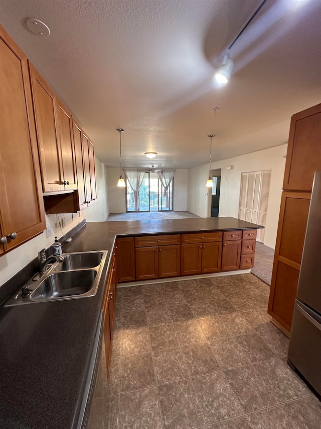 kitchen featuring pendant lighting, kitchen peninsula, sink, and a textured ceiling