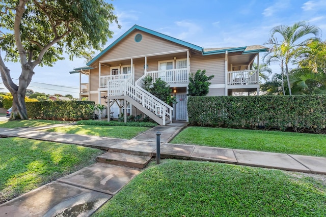 view of front facade with covered porch, stairway, and a front lawn