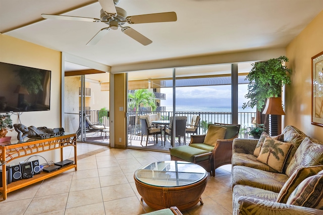 living room featuring a water view, ceiling fan, and light tile patterned floors