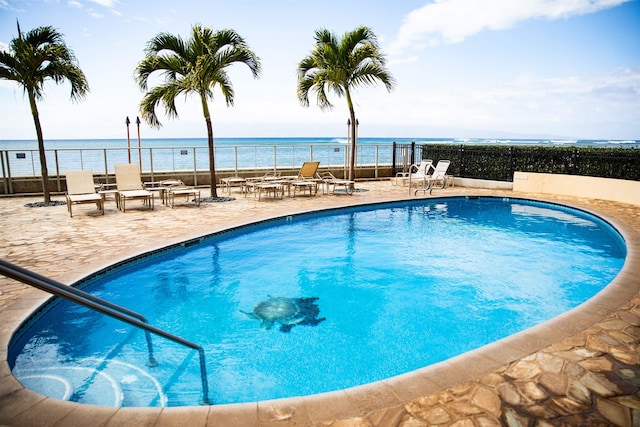 view of swimming pool with a patio area and a water view