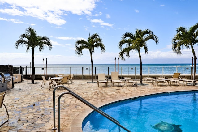 view of swimming pool with a patio, grilling area, and a water view