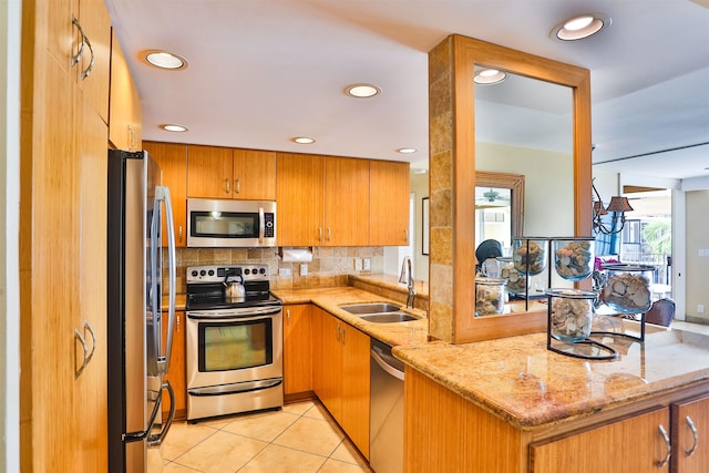 kitchen featuring kitchen peninsula, tasteful backsplash, light stone countertops, sink, and stainless steel appliances