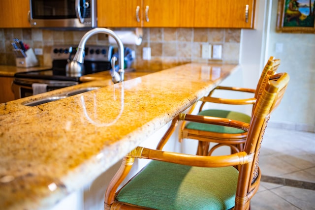 kitchen featuring sink, stainless steel appliances, light tile patterned floors, and tasteful backsplash