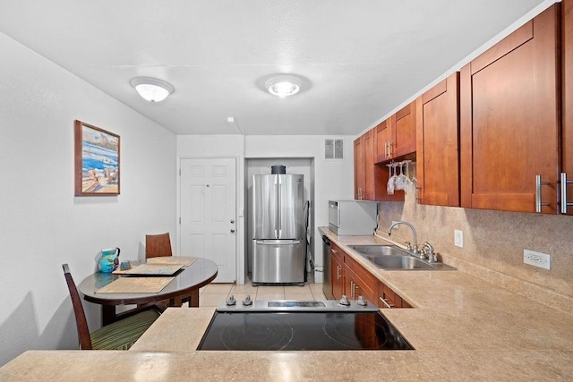 111 Kahului Beach Rd Unit D306, Kahului, HI 96732 - kitchen featuring freestanding refrigerator, a sink, tasteful backsplash, brown cabinetry, and light countertops