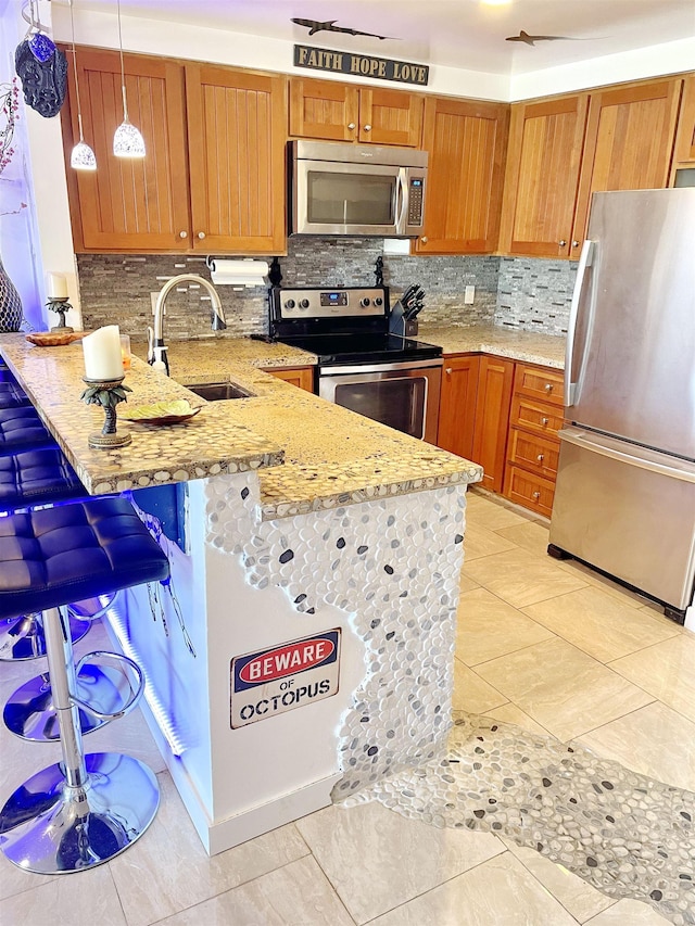 kitchen featuring a breakfast bar, sink, hanging light fixtures, appliances with stainless steel finishes, and kitchen peninsula