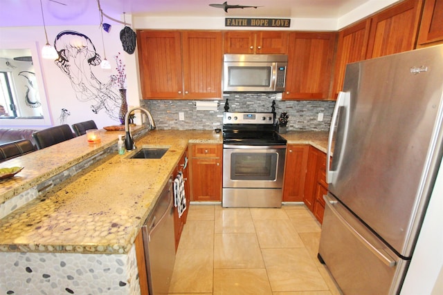 kitchen with pendant lighting, sink, appliances with stainless steel finishes, light stone counters, and decorative backsplash