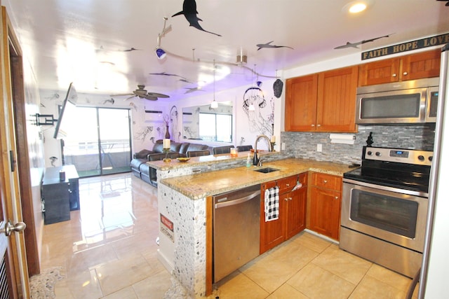 kitchen featuring stainless steel appliances, light stone countertops, sink, and kitchen peninsula