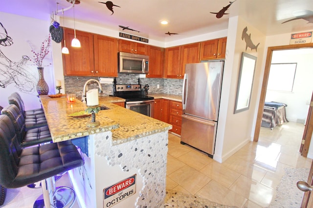 kitchen featuring decorative light fixtures, sink, a breakfast bar area, kitchen peninsula, and stainless steel appliances