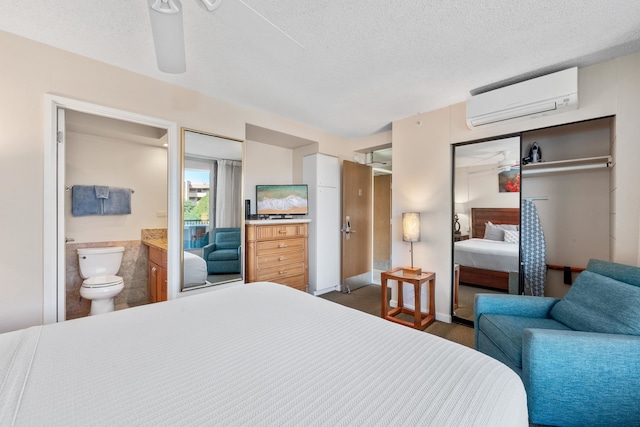 bedroom featuring connected bathroom, ceiling fan, a textured ceiling, a closet, and a wall unit AC