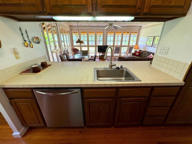 kitchen with dark wood-type flooring, ceiling fan, kitchen peninsula, dishwasher, and sink