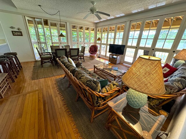 living room with ceiling fan, a textured ceiling, hardwood / wood-style floors, and a healthy amount of sunlight