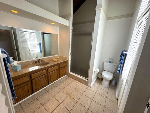 bathroom featuring toilet, tile floors, a shower with shower door, and vanity