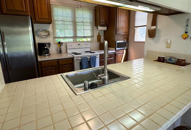 kitchen featuring plenty of natural light, tile counters, and appliances with stainless steel finishes