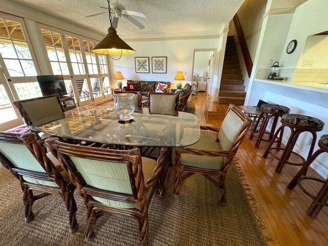 dining room featuring ceiling fan, a textured ceiling, hardwood / wood-style floors, and french doors