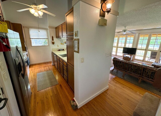 kitchen with ceiling fan, a textured ceiling, light hardwood / wood-style flooring, and stainless steel appliances