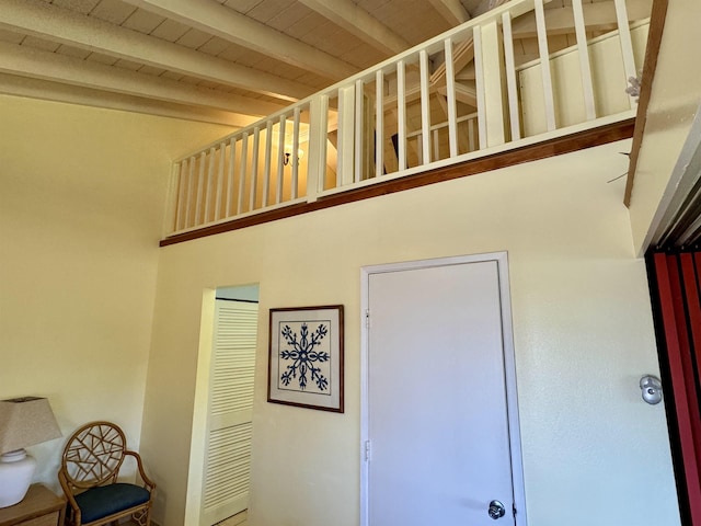 stairway with beam ceiling, wooden ceiling, and a towering ceiling