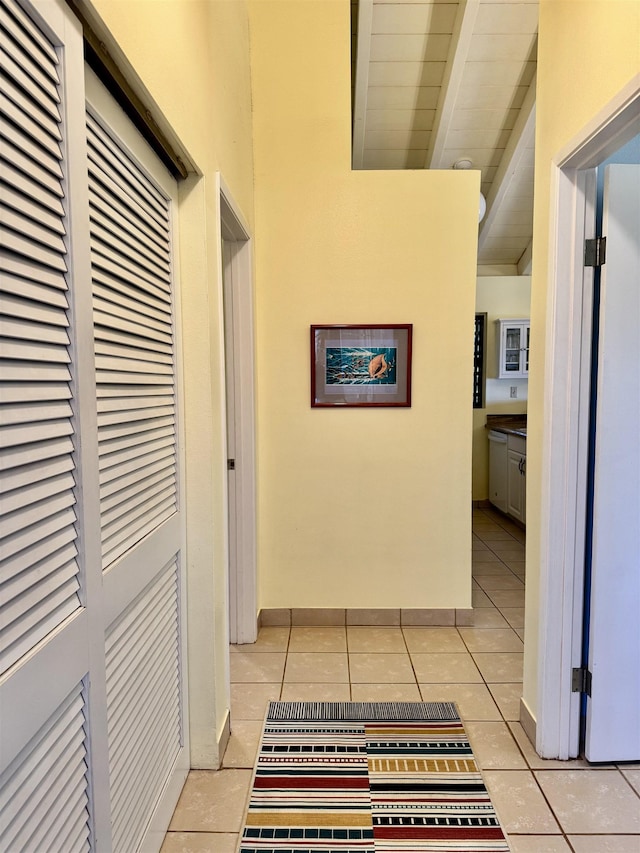 hallway with wood ceiling, light tile patterned floors, and beam ceiling