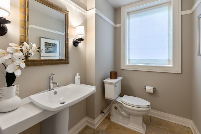 half bathroom featuring tile patterned flooring, toilet, baseboards, and a sink