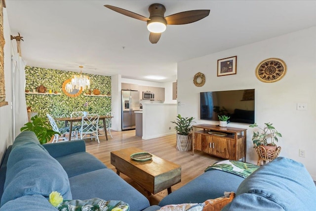 living room with ceiling fan with notable chandelier and light hardwood / wood-style flooring