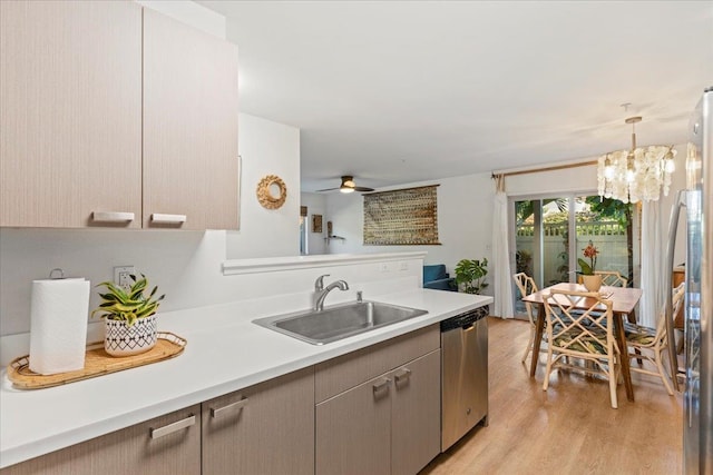 kitchen with sink, stainless steel appliances, pendant lighting, ceiling fan with notable chandelier, and light wood-type flooring