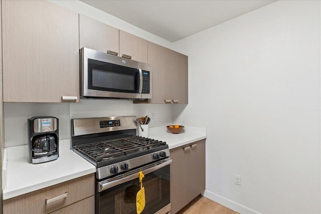 kitchen with light brown cabinets, light wood-type flooring, and appliances with stainless steel finishes