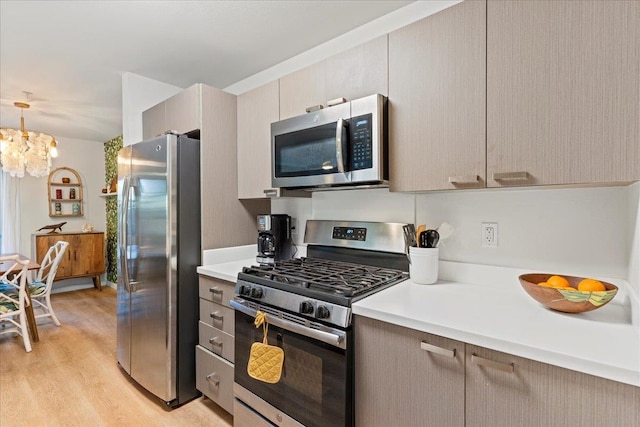 kitchen featuring an inviting chandelier, stainless steel appliances, decorative light fixtures, and light hardwood / wood-style floors