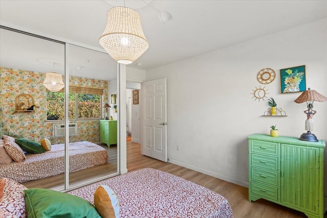 bedroom with a wall mounted AC, light hardwood / wood-style floors, and a closet