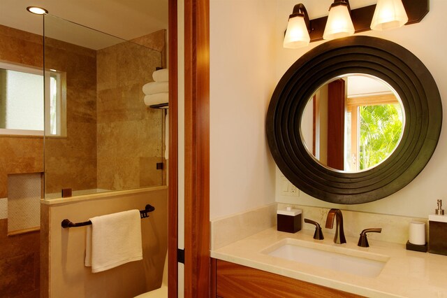 bathroom with tiled shower and vanity