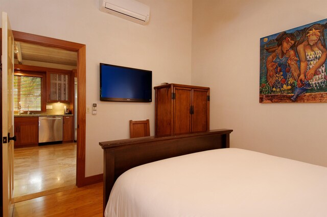 bedroom with a wall mounted AC and light hardwood / wood-style flooring