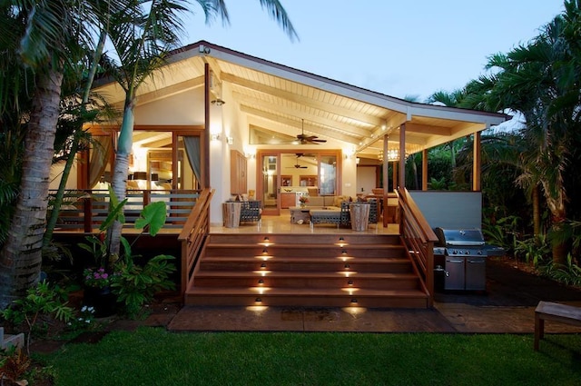 back house at dusk featuring ceiling fan, outdoor lounge area, and a wooden deck