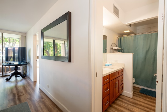 bathroom with wood-type flooring, toilet, and a healthy amount of sunlight