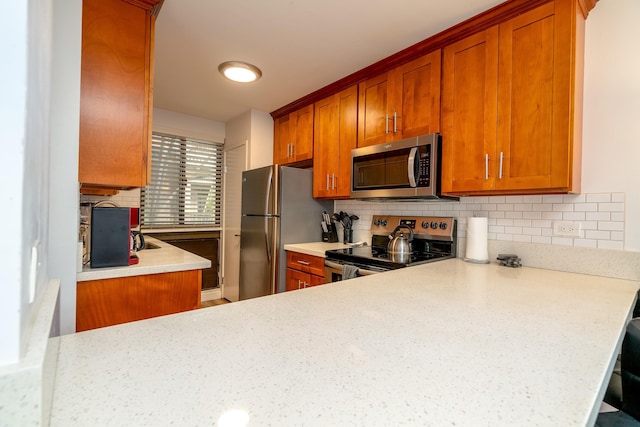 kitchen with backsplash, kitchen peninsula, light stone countertops, and stainless steel appliances