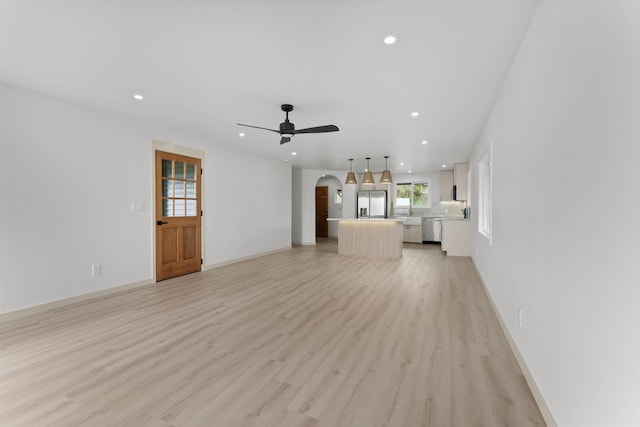 unfurnished living room with arched walkways, ceiling fan, recessed lighting, and light wood-type flooring