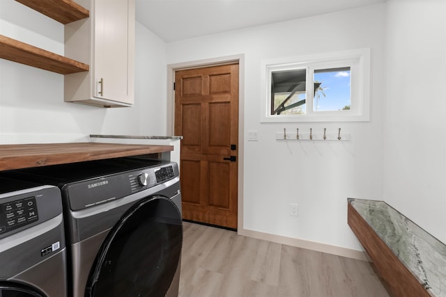 laundry area featuring cabinet space, baseboards, light wood finished floors, and washer and dryer