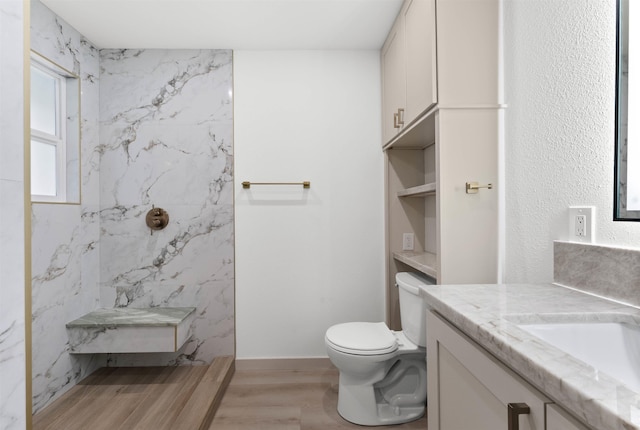 full bathroom featuring toilet, wood finished floors, vanity, and a marble finish shower